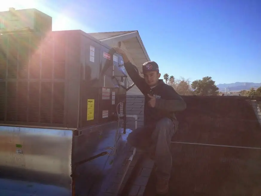 HVAC technician performing AC Tune-Up on a rooftop unit in Glen Ellyn
