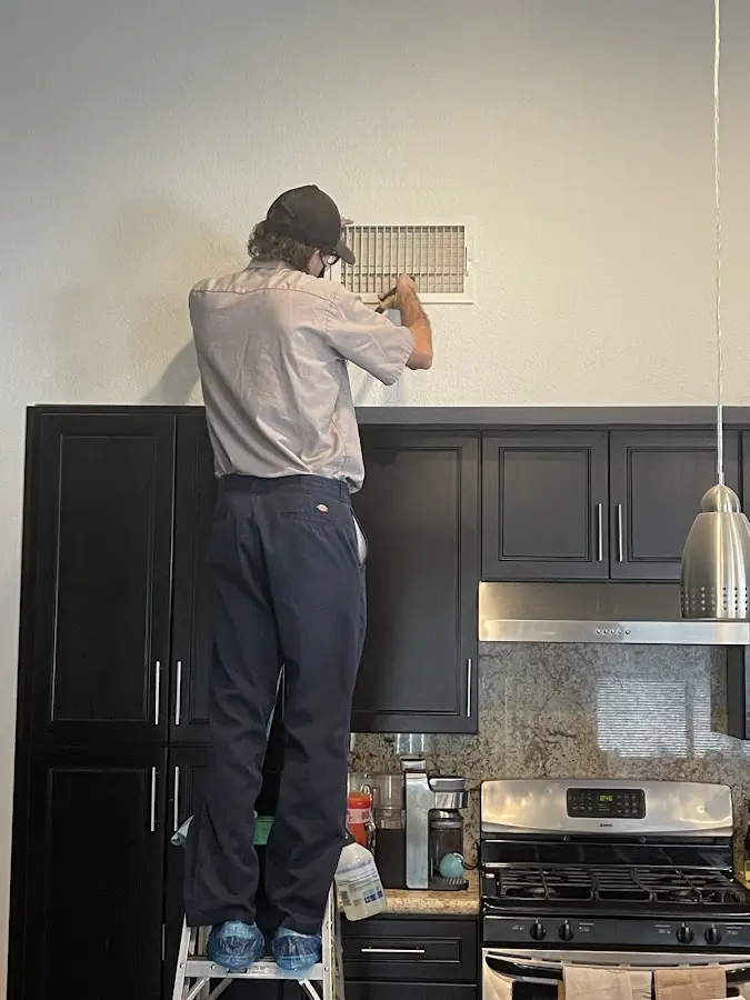 Technician inspecting an air vent during HVAC service in Glen Ellyn